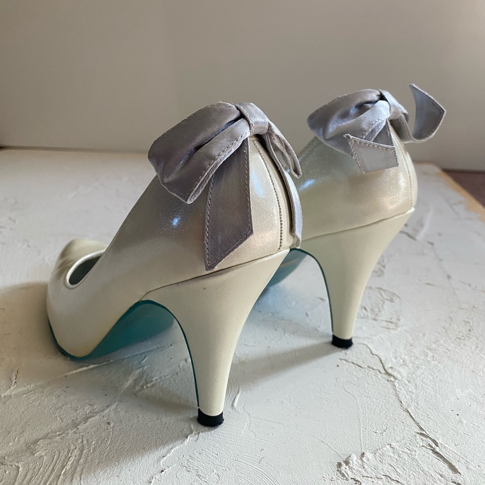 Pearl white patent leather heels with cute bow & a contrasting turquoise sole.